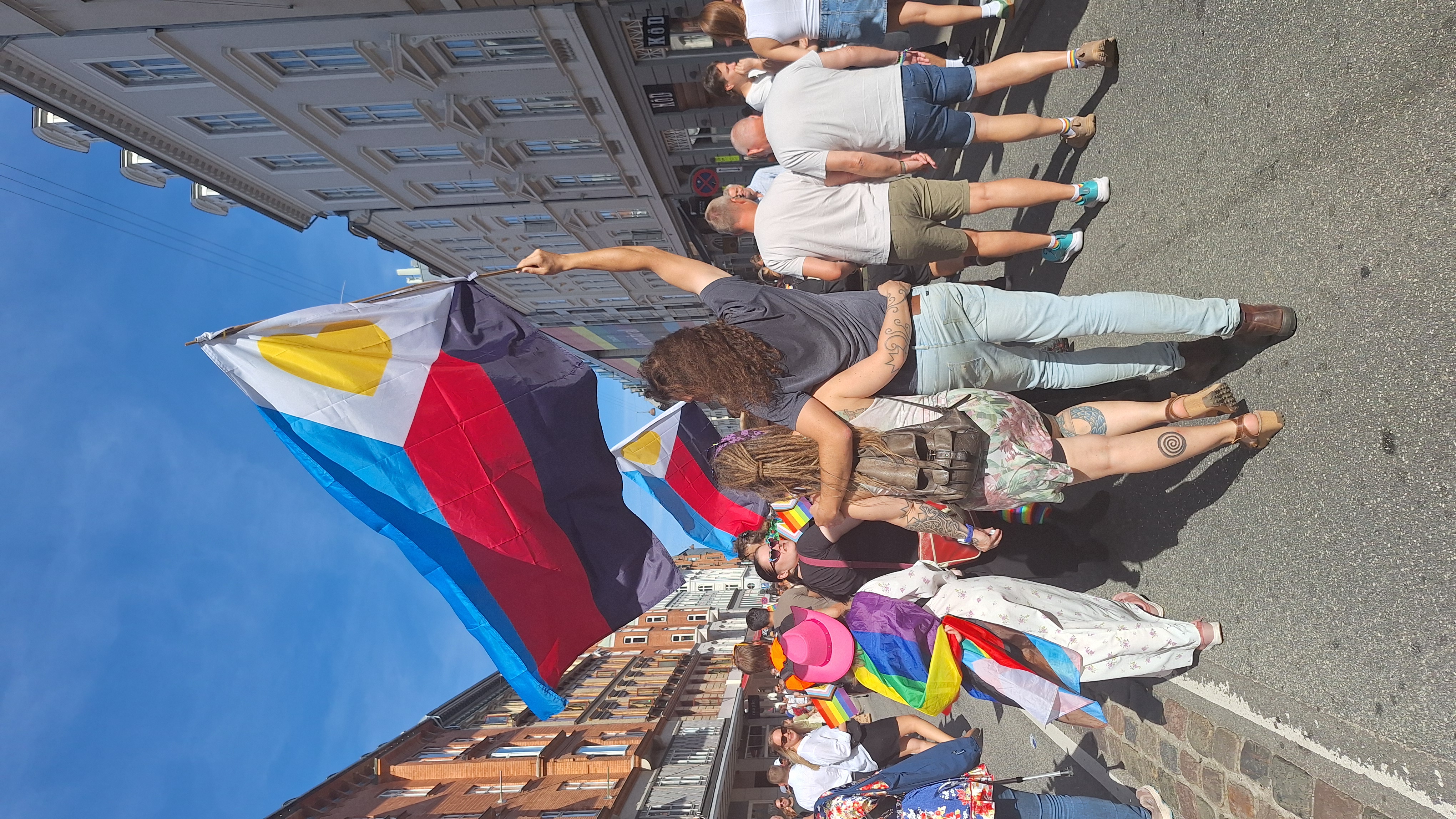 Person vifter med polyamori-flag ved Copenhagen Pride